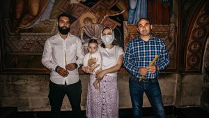 A family poses for a photo during a baptism ceremony in a church, highlighting religious tradition.
